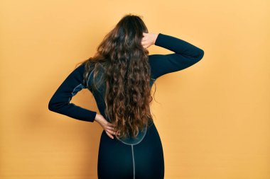 Genç İspanyol kız dalgıç neoprene üniformasını ters giyip elleri kafasında şüpheyi düşünüyor. 