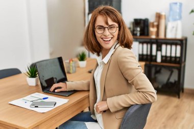 Ofiste çalışırken gülümseyen beyaz bir iş kadını..