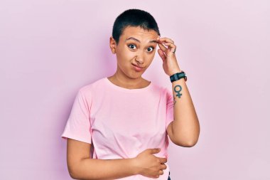 Kısa saçlı, sıradan pembe tişörtlü güzel bir İspanyol kadın. Alnındaki sorun yüzünden endişeli ve stresli. Kriz için endişeli. 