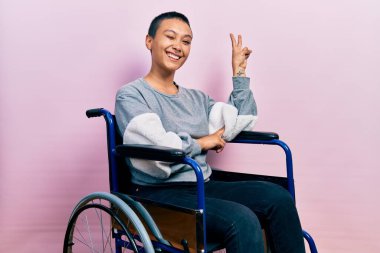 Tekerlekli sandalyede oturan, gülümseyen, kameraya göz kırpan, zafer işareti yapan, kısa saçlı güzel İspanyol kadın. İki numara.. 