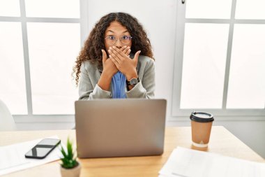 Ofisteki masasında oturan güzel İspanyol iş kadını laptopla çalışırken ağzını yanlışlıkla ellerle kapatarak şok geçirdi. gizli kavram. 