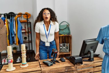 Güzel İspanyol kadın giyim mağazasında çalışıyor. Korkmuş ve ağzı açık kalmış, şaşırmış ve şaşırmış. 