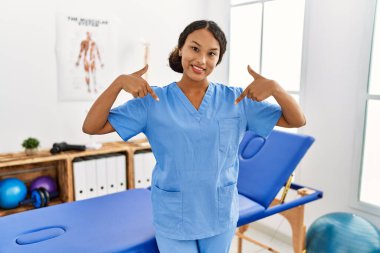 Güzel İspanyol fizyoterapist kadın ağrı kesici kliniğinde kendine güveni tam görünüyor, kendini gururlu ve mutlu gösteriyor.. 