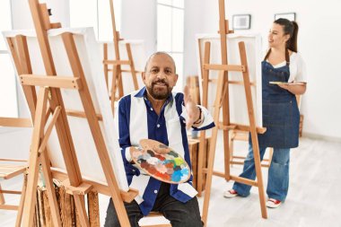 Sanat stüdyosundaki kıdemli sanatçı dostça bir selamlama ve hoş geldin hediyesi olarak el sıkışmayı sunuyor. başarılı iş. 