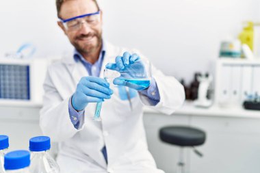 Orta yaşlı, labaratuarda çalışan bilim adamı üniforması giyen bir İspanyol.