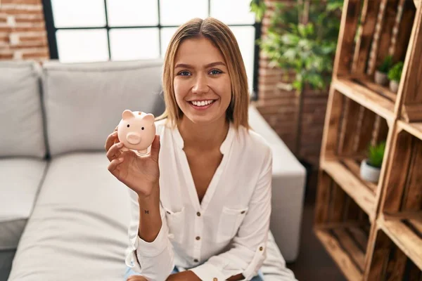 Jong Blond Vrouw Holding Piggy Bank Kijken Positief Gelukkig Staan — Stockfoto
