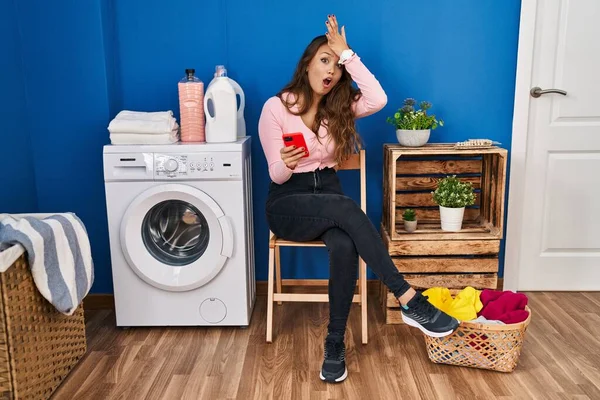 Çamaşır yıkamak için bekleyen Latin kökenli genç bir kadın akıllı telefon kullanıyor. Hatalı olduğunu unutma. Unuttum, kötü hafıza kavramı. 