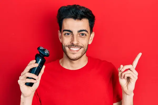 Jonge Spaanse Man Houdt Elektrische Scheermes Machine Glimlachen Blij Wijzend — Stockfoto