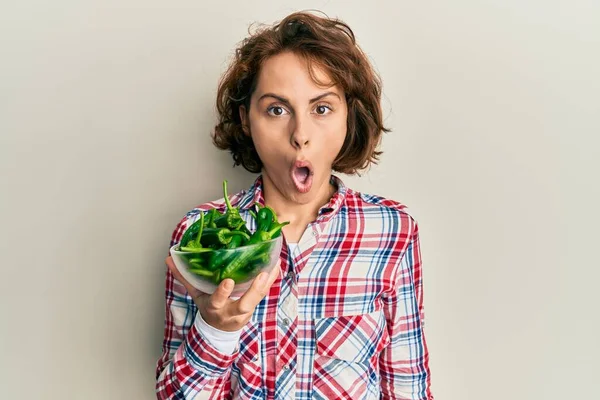 Young Brunette Woman Holding Bowl Green Peppers Scared Amazed Open — Stock Photo, Image