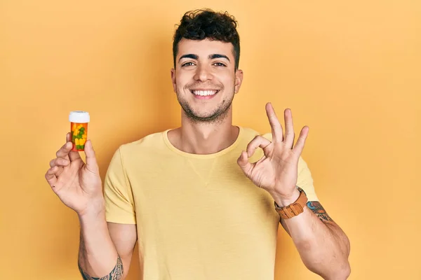 Молодий Іспаномовний Чоловік Тримає Таблетки Роблячи Знак Пальцями Посміхаючись Дружній — стокове фото