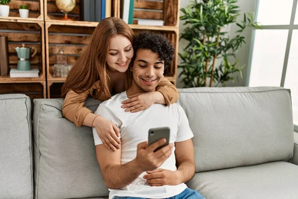 年轻夫妇快乐地微笑着 拥抱着坐在家里的沙发上 — 图库照片