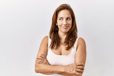 Orta yaşlı İspanyol bir kadın soyutlanmış arka planda duruyor gülümsüyor ve yan tarafa bakıyor.. 