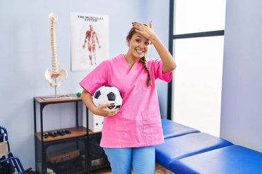 Fizyoterapi kliniğinde çalışan genç İspanyol kadın futbol topunu tutarken gergin ve hayal kırıklığına uğramış, şaşırmış ve sinirli bir yüz ifadesi takındı. 