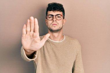 Günlük kıyafetler giyen ve gözlük takan İspanyol genç adam avucunun içi gibi şarkı söylemeyi kesiyor. Yüzünde olumsuz ve ciddi bir jest olan uyarı ifadesi. 