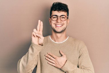 Gündelik kıyafetler ve gözlük takan genç İspanyol adam gülümsüyor. Göğsü ve parmakları havada küfür ediyor. Sadakat yemini ediyor. 