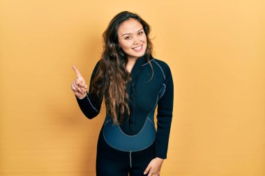 Dalgıç neoprene üniforması giyen genç İspanyol kız başarılı bir fikirle işaret ediyor. Heyecanlı ve mutlu. Bir numara.. 