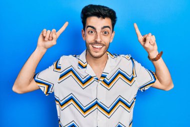 Gündelik kıyafetler giyen genç İspanyol adam şaşırmış, şaşırmış ve parmaklarıyla işaret ediyor ve kollarını kaldırıyordu.. 