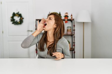 Genç Latin kadın Noel dekorunun yanında oturmuş el ele tutuşarak bağırıyor ve çığlık atıyordu. iletişim konsepti. 