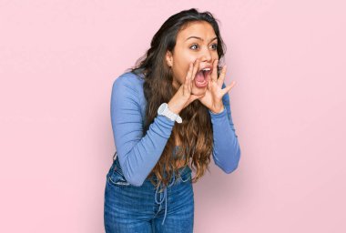Gündelik kıyafetler giyen genç İspanyol kız elleri ağızda bağırarak bağırıyor. 