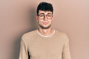 Gündelik kıyafetler ve gözlük takan genç İspanyol adam uykulu ve yorgun görünüyor, yorgunluktan yorgun ve akşamdan kalma, sabahları tembel gözler.. 