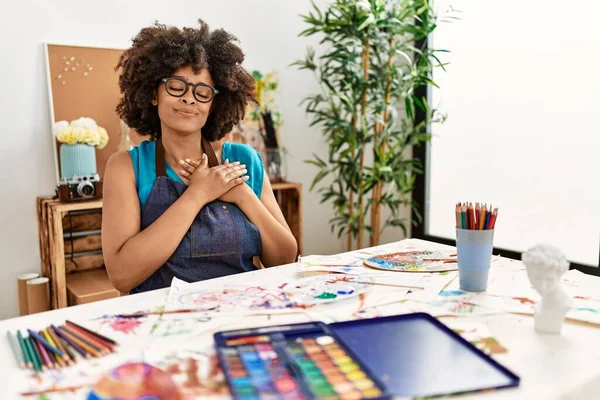 美丽动人的非洲裔美国女人 在艺术工作室里画着非洲裔的头发 双手放在胸前 闭着眼睛 脸上挂着感激的手势 健康概念 — 图库照片