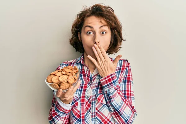 Young Brunette Woman Holding Bowl Salty Biscuits Covering Mouth Hand — Stock Photo, Image