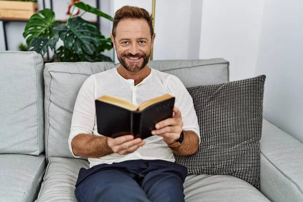 Middle Age Hispanic Man Smiling Confident Reading Book Home — стоковое фото
