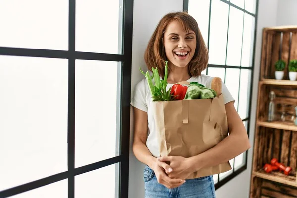 若い白人女性は自信を持って食料品の袋を持って笑顔自宅で — ストック写真