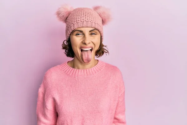 面白い表情で幸せ舌を突き出すかわいいウールキャップを身に着けている若いブルネットの女性 感情の概念 — ストック写真