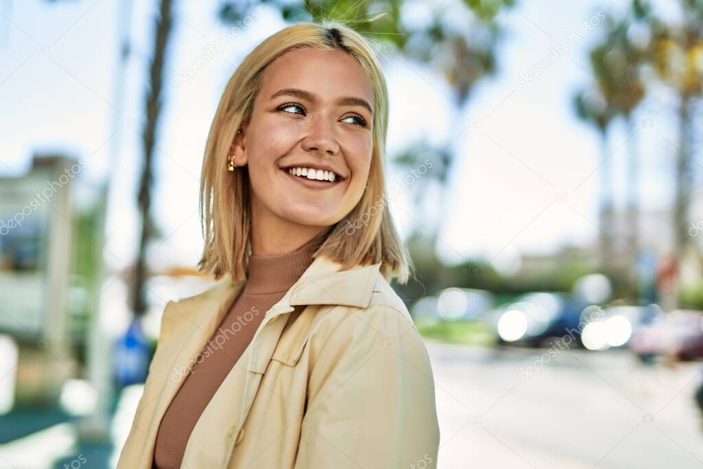 Young blonde girl smiling happy standing at the city.