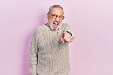 Sakallı, sıradan süveterli ve gözlüklü yakışıklı bir adam kameraya kızgın ve sinirli bir şekilde bakıyor. 