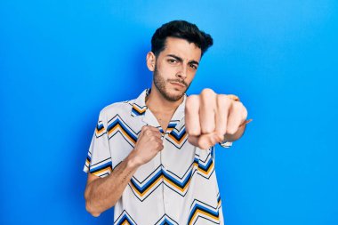 Latin kökenli genç adam gündelik kıyafetler giyiyor. Yumruk yumruğa dövüşüyor, agresif ve öfkeli saldırı, tehdit ve şiddet uyguluyor. 