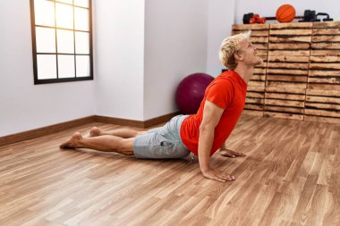 Young caucasian man smiling confident training yoga at sport center