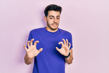 Gündelik tişört giyen genç İspanyol adam tiksindirici bir ifade takınıyor, tiksindirici bir yüz ifadesi takınıyor ve tiksindirici bir ifade takınıyor.. 