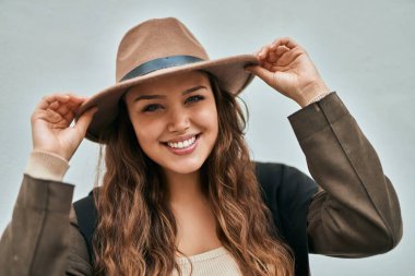 Genç İspanyol turist kadın gülümseyerek şehirde şapkasını tutarken mutlu..