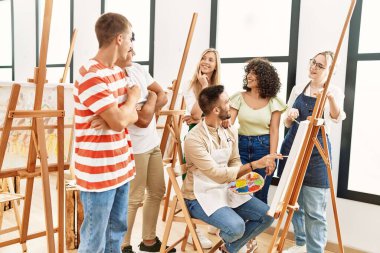 Mutlu gülümseyen ve ortak arayan bir grup insan sanat stüdyosunda..