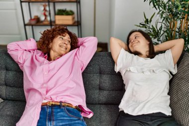 Olgun anne ve Down sendromlu kız evde kanepede dinleniyor.