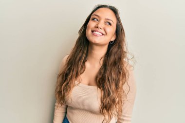 Latin kökenli genç bir kız, günlük giysiler giyiyor. Tarafını arıyor, profil pozu veriyor. Doğal bir yüz ve kendine güvenen bir gülümseme.. 