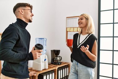 İki iş adamı gülümsüyor, ofiste kahve içiyorlar..