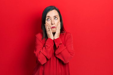 Orta yaşlı İspanyol kadın gündelik kıyafetler giyiyor. Yorgun eller, yüzünü kapatıyor. Depresyon ve üzüntü yaşıyor. 