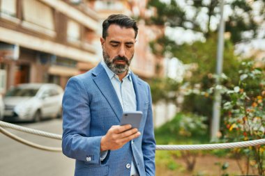 Şehirde akıllı telefon kullanan orta yaşlı bir işadamı..