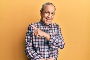 Yakışıklı, gri saçlı, rahat tişörtlü, neşeli yüzlü, elleri ve parmaklarıyla yüzünü gösteren mutlu ve doğal bir ifadeyle yakışıklı bir adam. 