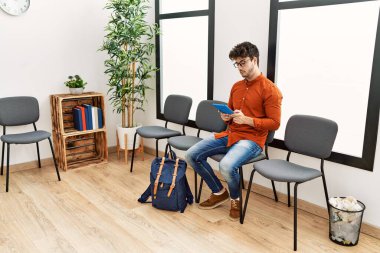 Genç İspanyol adam bekleme odasında dokunmatik ped kullanıyor.