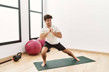 Genç İspanyol adam gülümsüyor spor merkezinde esniyor.