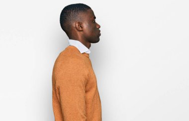 Afro-Amerikalı genç bir adam günlük giysiler giymiş, rahat bir görünüm takınıyor, doğal bir yüz ifadesi ve kendine güvenen bir gülümsemeyle poz veriyor.. 