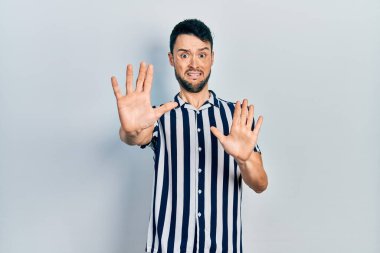 Günlük giysiler giyen genç İspanyol adam korku ifadesinden korkuyor ve dehşete düşüyor. El hareketlerini durdur, şok içinde bağır. panik konsepti. 