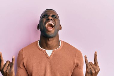 Sıradan kıyafetler giymiş, çılgın bir ifadeyle bağıran, elleri havada rock sembolü yapan genç bir Afrikalı Amerikalı. Müzik yıldızı. ağır kavram. 