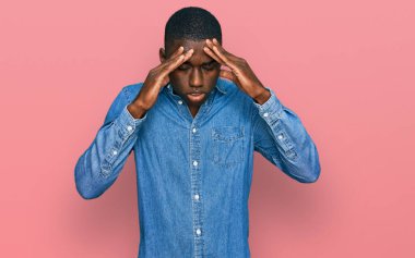 Genç Afro-Amerikan adam stres yüzünden elleri başının üstünde gündelik giysiler giyiyor. migren ağrısı. 