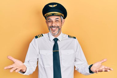 Yakışıklı, orta yaşlı, gri saçlı, uçak pilotu üniforması giyen neşeli gülümseyen, yardım eli uzatan ve kabul gören bir adam.. 