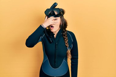 Genç İspanyol kız dalgıç neoprene üniforması giyiyor. Şoka girip yüzünü ve gözlerini eliyle kapatıyor. Korkuyla parmaklarından bakıyor. 